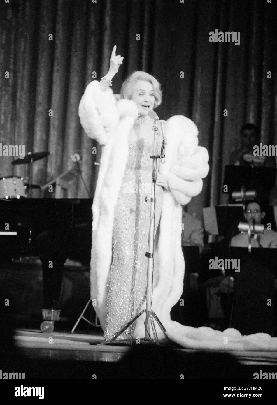 26 MAGGIO 1964 Dietrich va verso est. Questo comodo per il cappotto di pelliccia leggermente datato non è sicuramente a causa della temperatura, è probabilmente una concessione alla moda russa, ma chi lo indossa è più aggiornato che mai. E' Marlene Dietrich, che canta per la prima volta a Mosca, e stupisce il pubblico. Persino un fan sul palco per congratularsi con lei. Ma si astiene dal cantare la sua famosa Lilli Marlene, per evitare di sconvolgere la sensibilità russa in tempo di guerra, e secondo quanto riferito le spararono ai nuovi che la interrogavano sulla sua età e sulla sua paga. Mosca, URSS Foto Stock