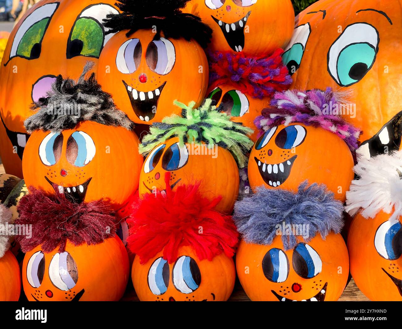 Vivace collezione di zucche dipinte con volti felici e stravaganti, ognuna con diversi filati colorati Foto Stock