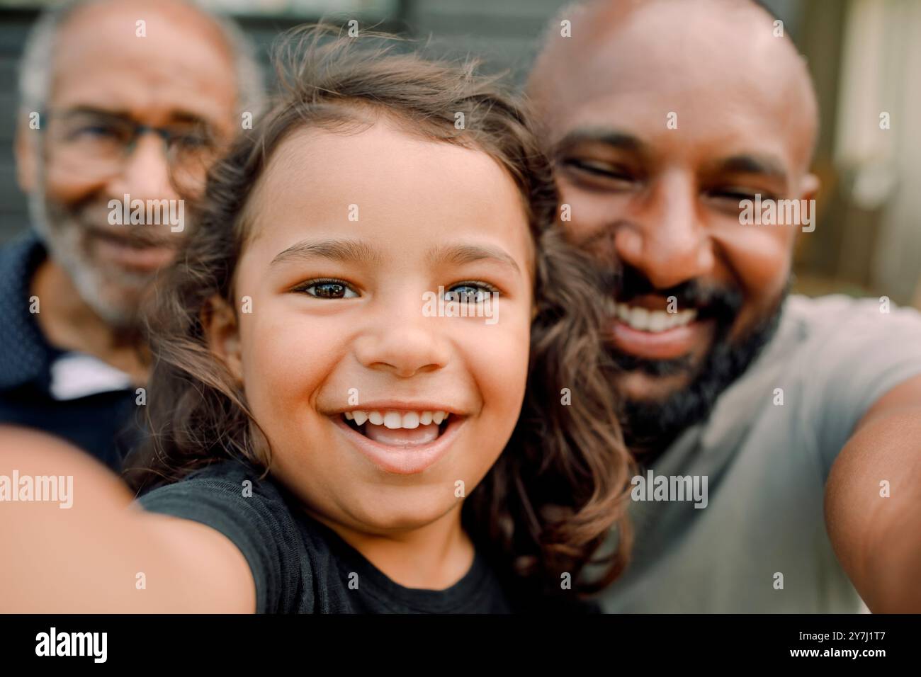 Ritratto ravvicinato di un ragazzo sorridente che scatta selfie con padre e nonno Foto Stock