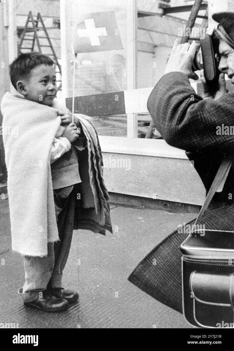 RAGAZZO TIBETANO DETIENE LA BANDIERA SVIZZERA ALL'AEROPORTO DI ZURIGO, IN SVIZZERA; 21 MARZO 1964 Foto Stock