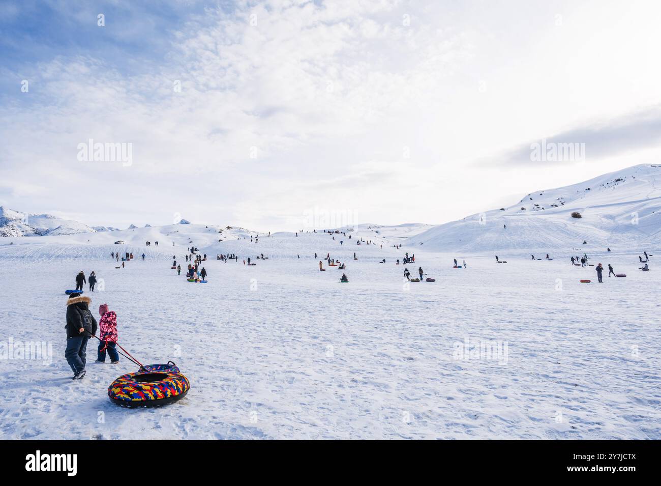 Le persone si rilassano e scivolano giù per lo scivolo con il tubing in inverno nella natura delle montagne del Kazakistan. Shymkent, Kazakistan - 27 gennaio 2024 Foto Stock