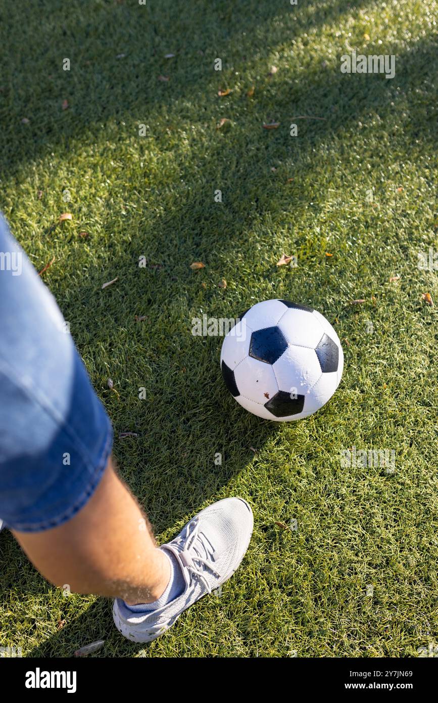 Calcio su erba, persona che indossa sneakers e pantaloncini denim Foto Stock