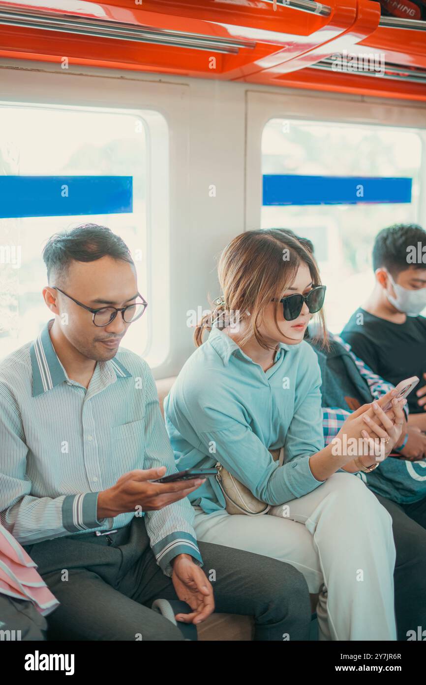 I pendolari della metropolitana sono coinvolti nei loro telefoni mentre navigano nella trafficata città Foto Stock