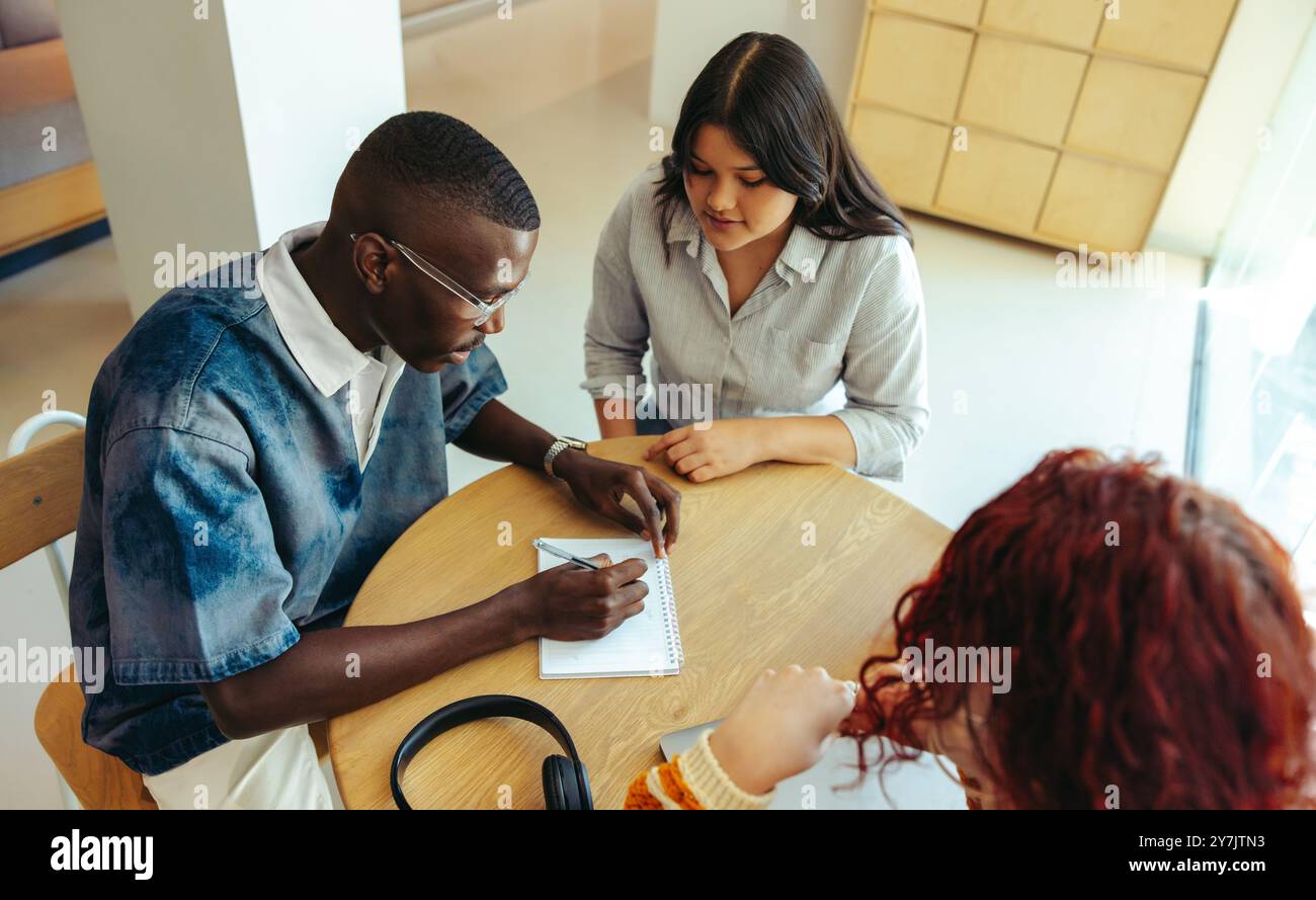 Un gruppo di studio diversificato che lavora insieme in un ambiente universitario, sottolineando la collaborazione, la comunicazione e il successo accademico tra gli studenti universitari. Foto Stock