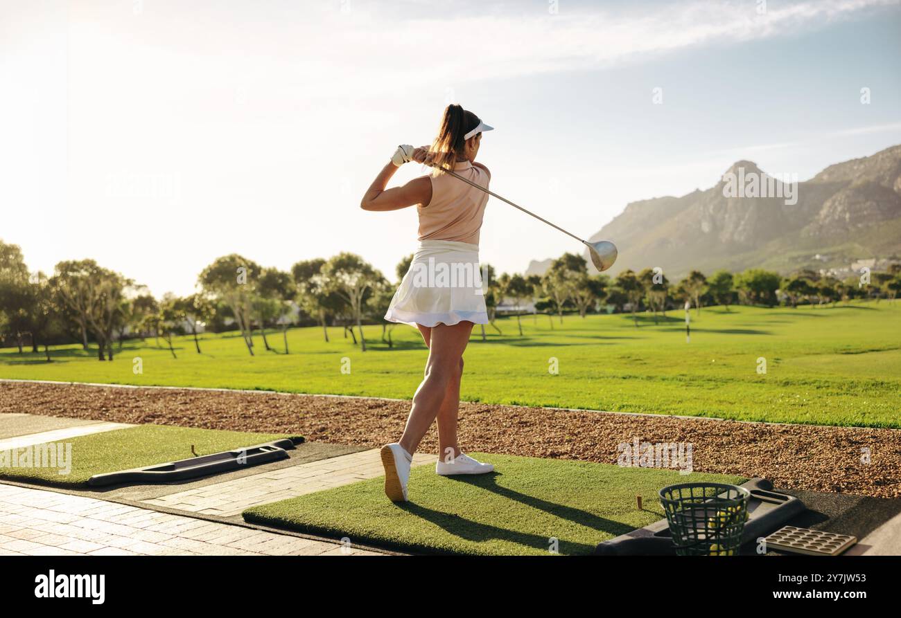 Golfista professionista che pratica il suo swing perfetto su uno splendido e panoramico campo da golf. Cattura un momento di sport e concentrazione. Foto Stock