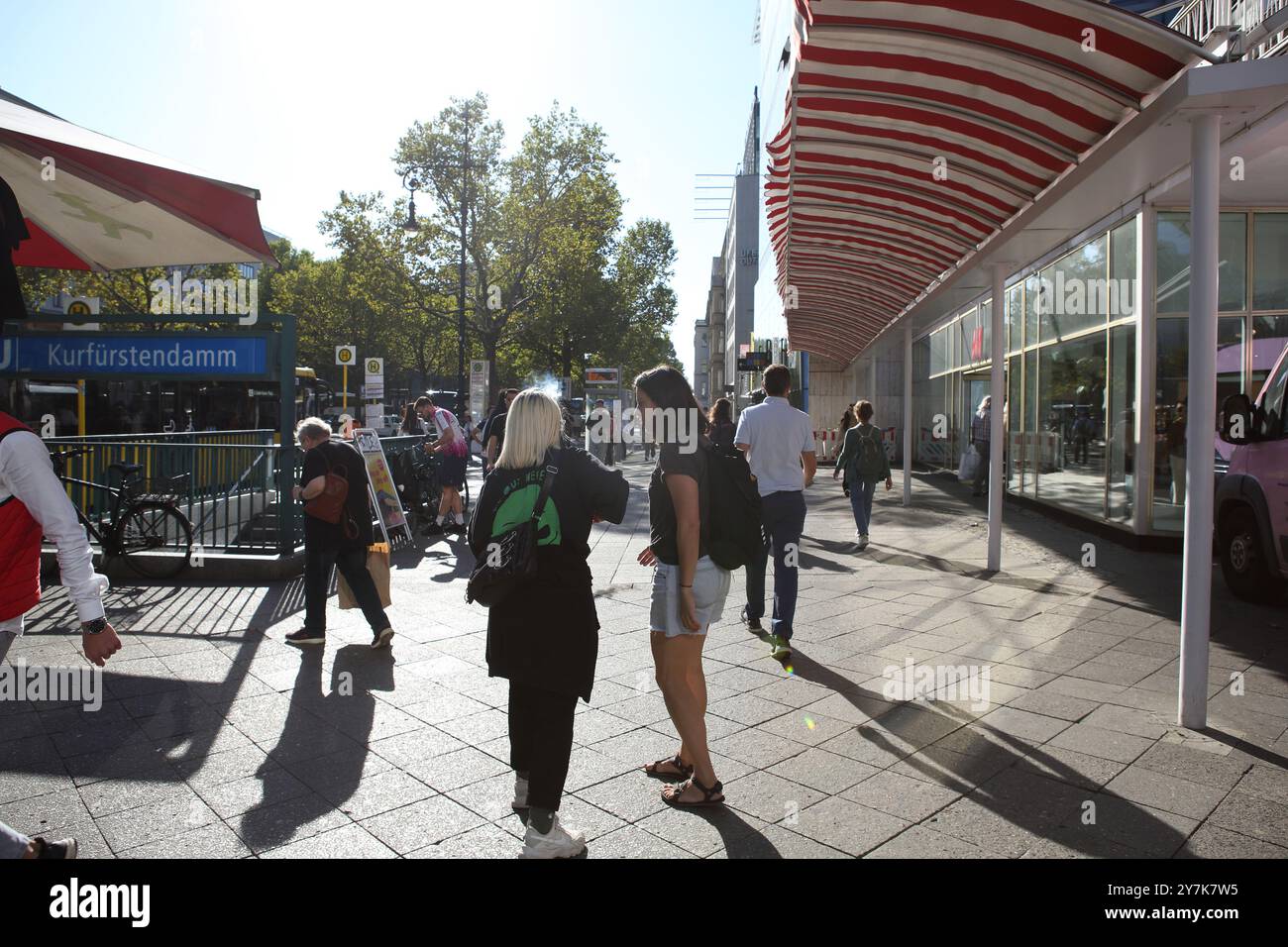 Le riprese contro la fotocamera solare catturano persone con silhouette, due donne incluse, camminano e parlano sul marciapiede di Kurfurstendamm, una strada commerciale Foto Stock