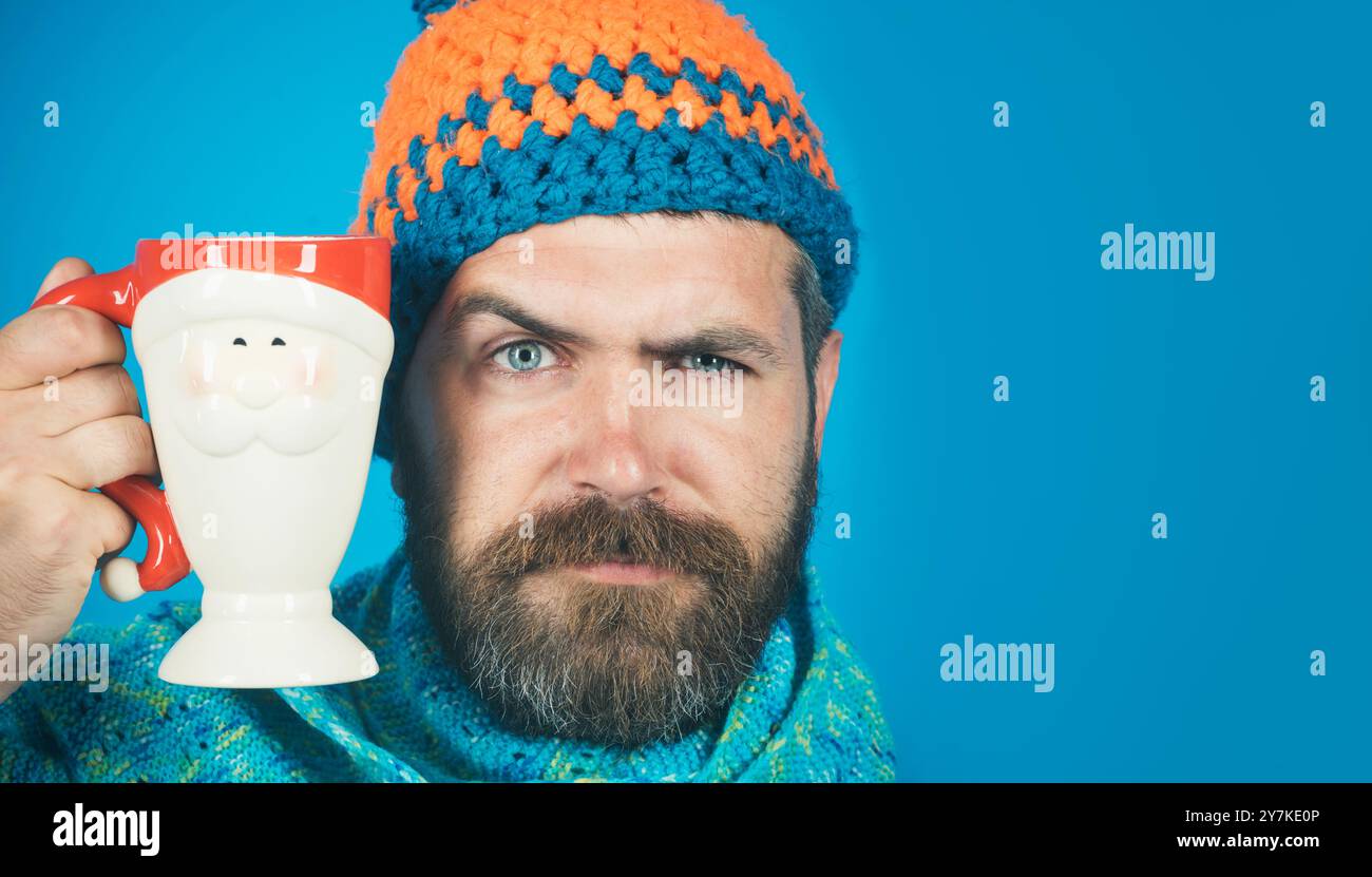 Ritratto dell'uomo barbuto in cappello e sciarpa con tazza di caffè o tè. Uomo elegante con barba e baffi con tazza di caffè o cappuccino. Uomo serio Foto Stock