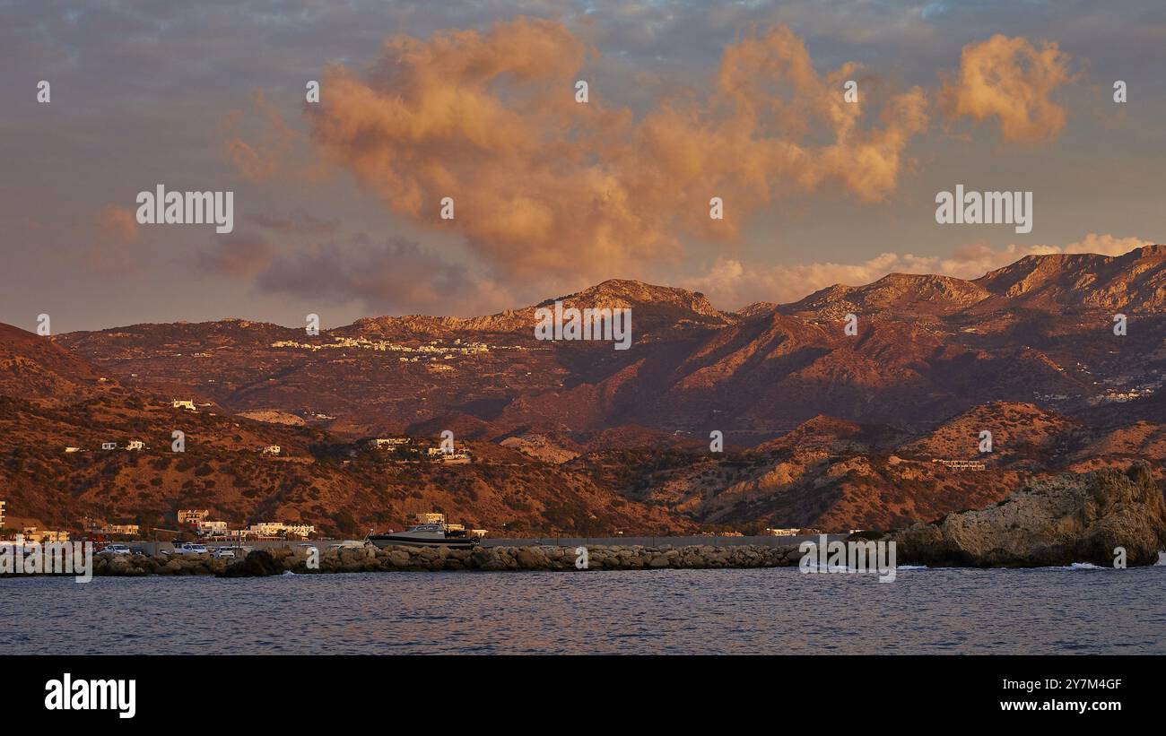 Suggestivo paesaggio costiero all'alba, con spettacolari nuvole e montagne sullo sfondo, Pigadia, città e porto, Pigadia Bay, città principale, Karpathos, fallo Foto Stock