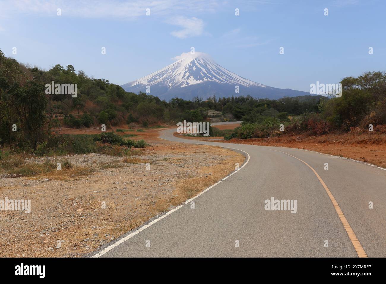 Una strada di montagna vuota in una giornata limpida con vista sul Monte Fuji sullo sfondo. Foto Stock