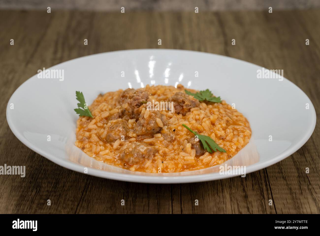 Risotto italiano servito con salsiccia e salsa di pomodoro su un letto di riso. Foto Stock