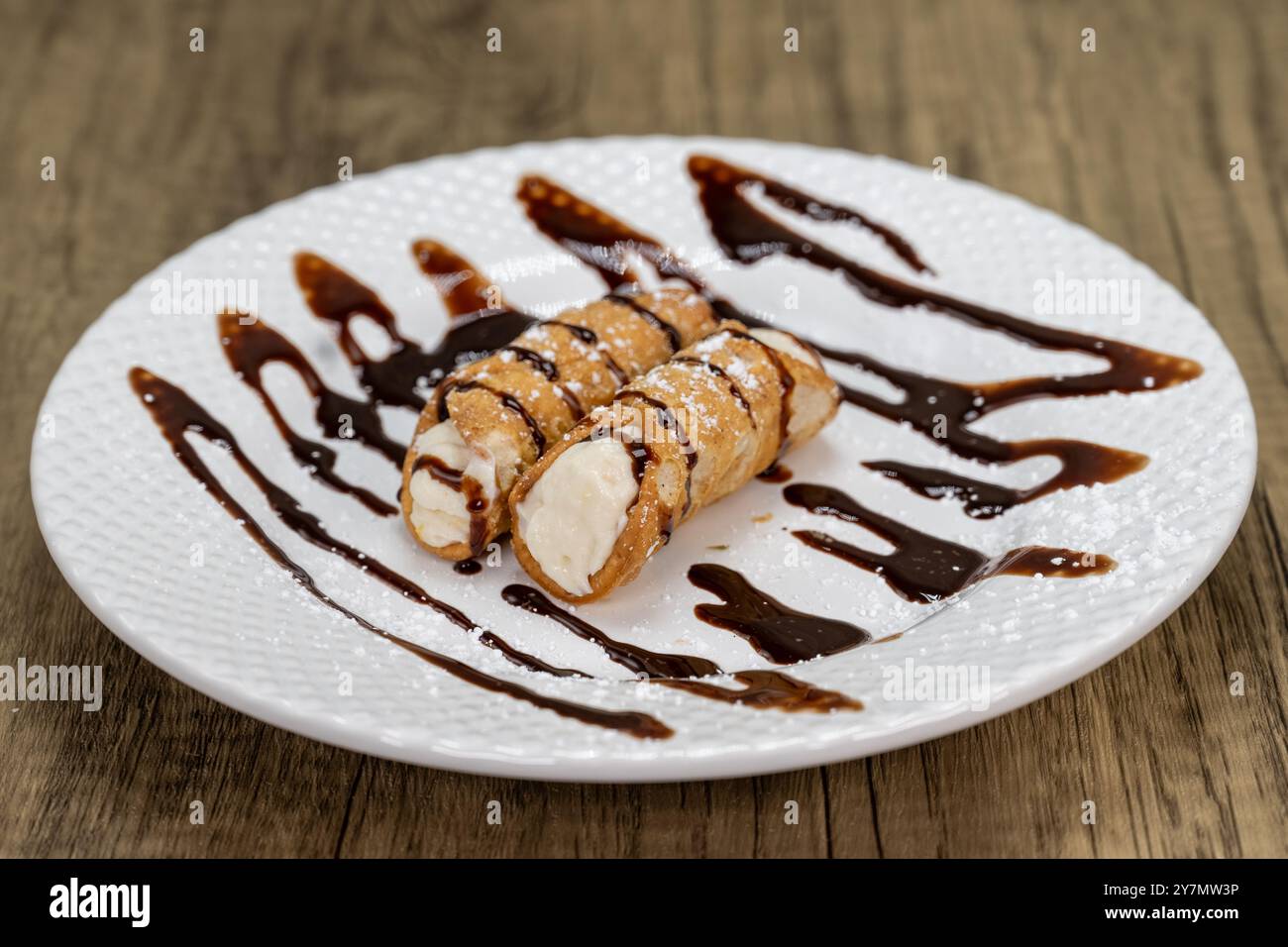 Viene servito un dessert tradizionale italiano composto da cannoli conditi con sciroppo al cioccolato. Foto Stock