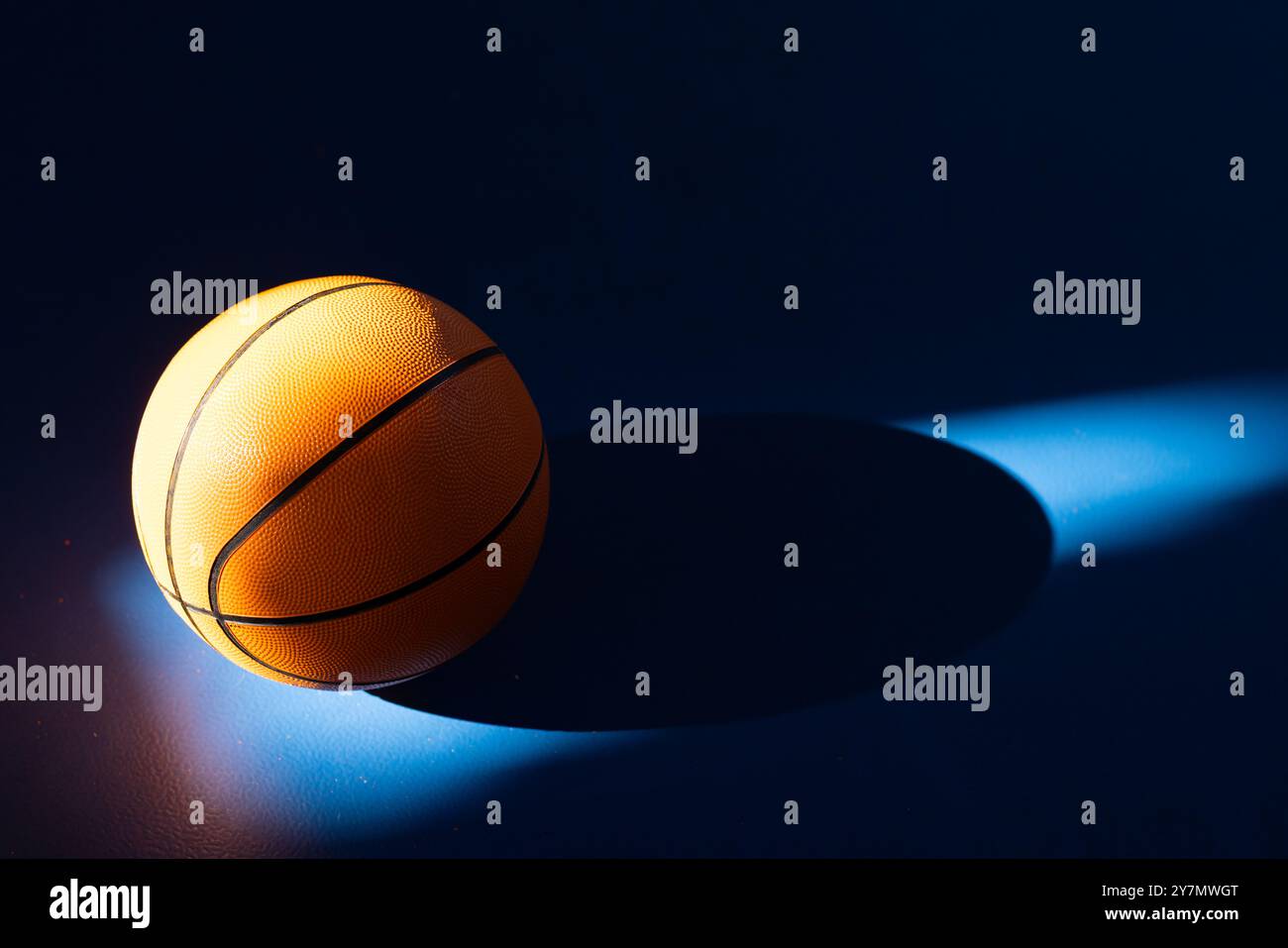 Pallacanestro che riposa sul campo sotto luci e ombre spettacolari, copia spazio Foto Stock