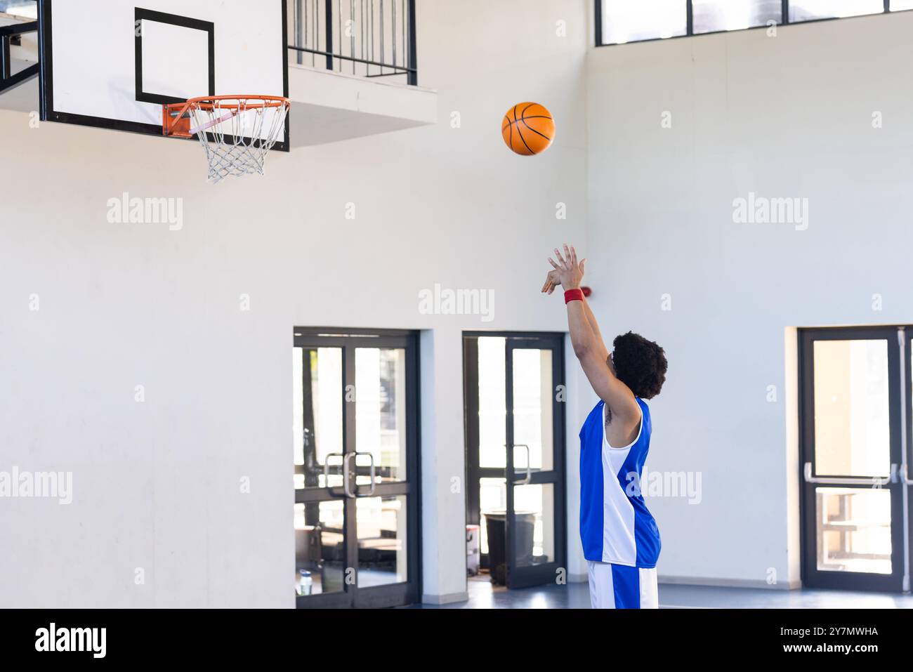 Giocare a basket, uomo che spara palla verso il cerchio in un campo al coperto Foto Stock