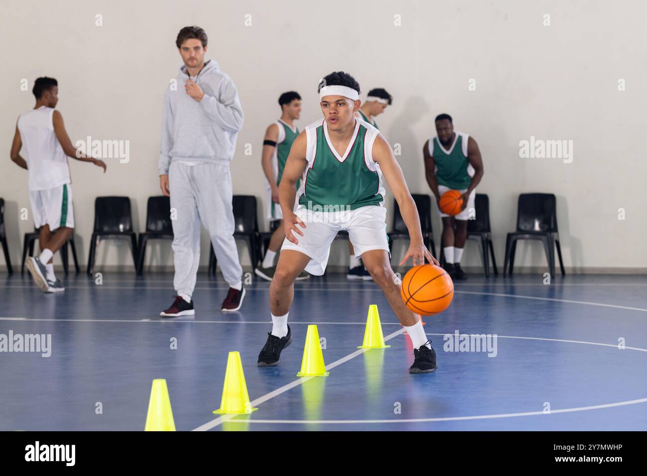 Dribbling di pallacanestro intorno ai coni, giovane atleta che pratica nella palestra scolastica Foto Stock