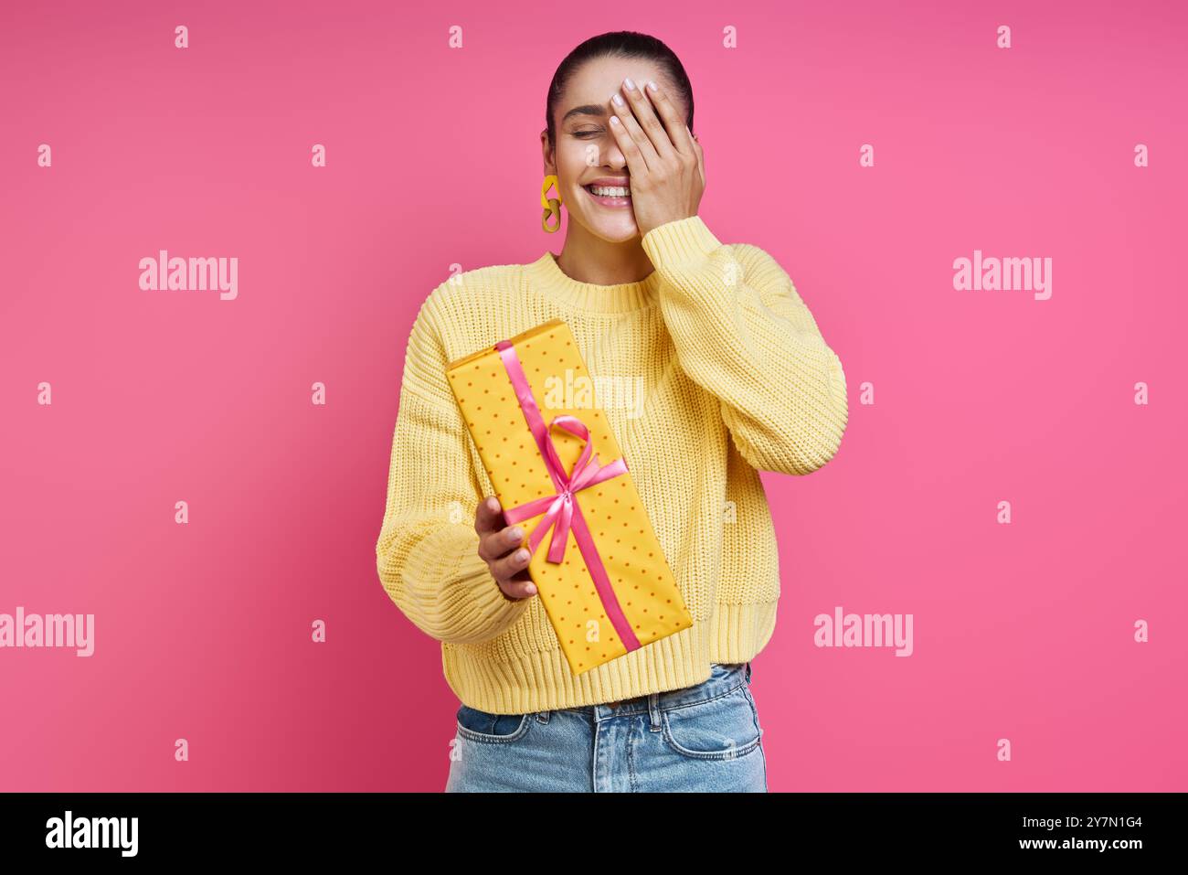Bella giovane donna che tiene in mano una confezione regalo e sorride su sfondo colorato Foto Stock Bella giovane donna che tiene in mano una confezione regalo e sorride su sfondo colorato Foto Stock