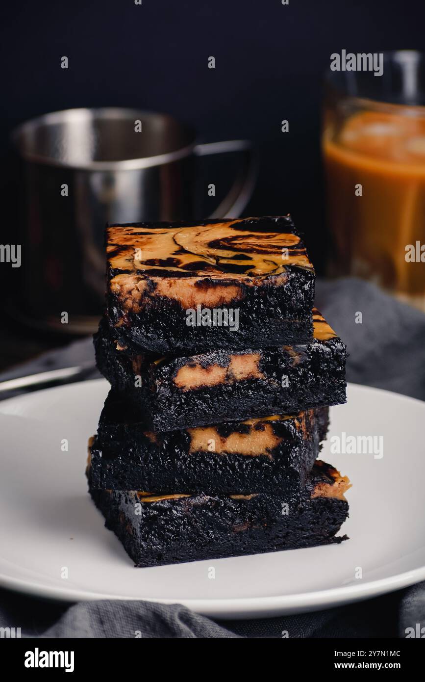 Pila di brownie al cioccolato scuro con una turbolenza al caffè vietnamita: Brownie fudgy realizzati con cacao nero in polvere e una turbolenza di caffè più leggera Foto Stock