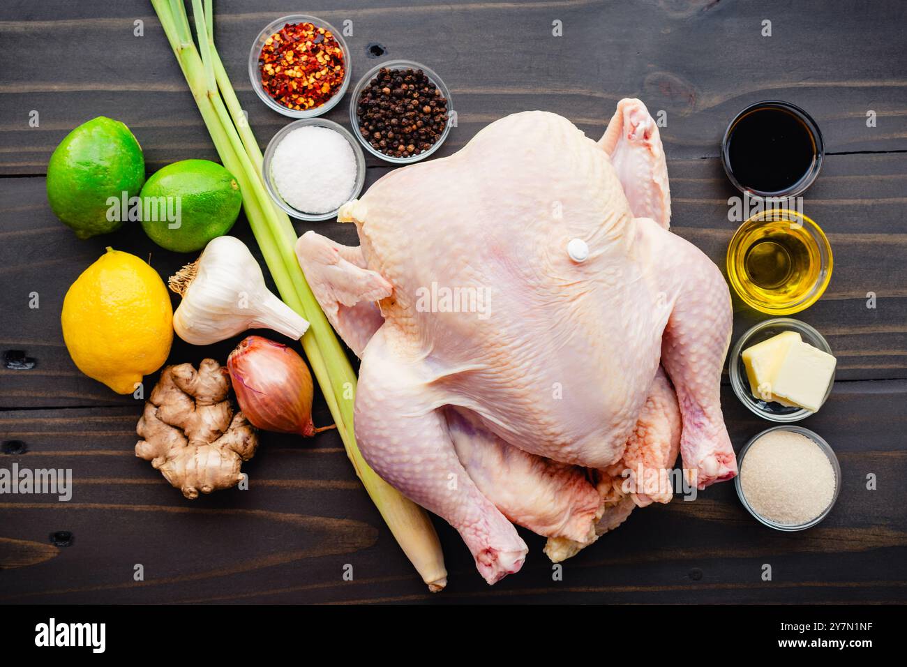 Ingredienti vietnamiti di pollo arrosto: Pollo intero circondato da citronella, limes, limone, aglio, zenzero, salsa di pesce e molto altro su un tavolo di legno Foto Stock