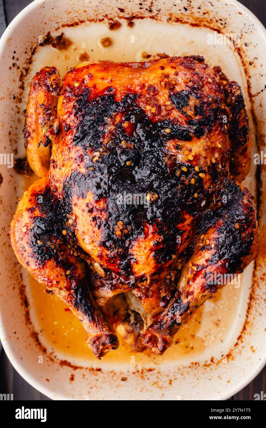 Primo piano di pollo arrosto vietnamita in piatto da forno: Pollo arrosto intero glassato marrone dorato in un piatto da forno in gres di ceramica bianco Foto Stock