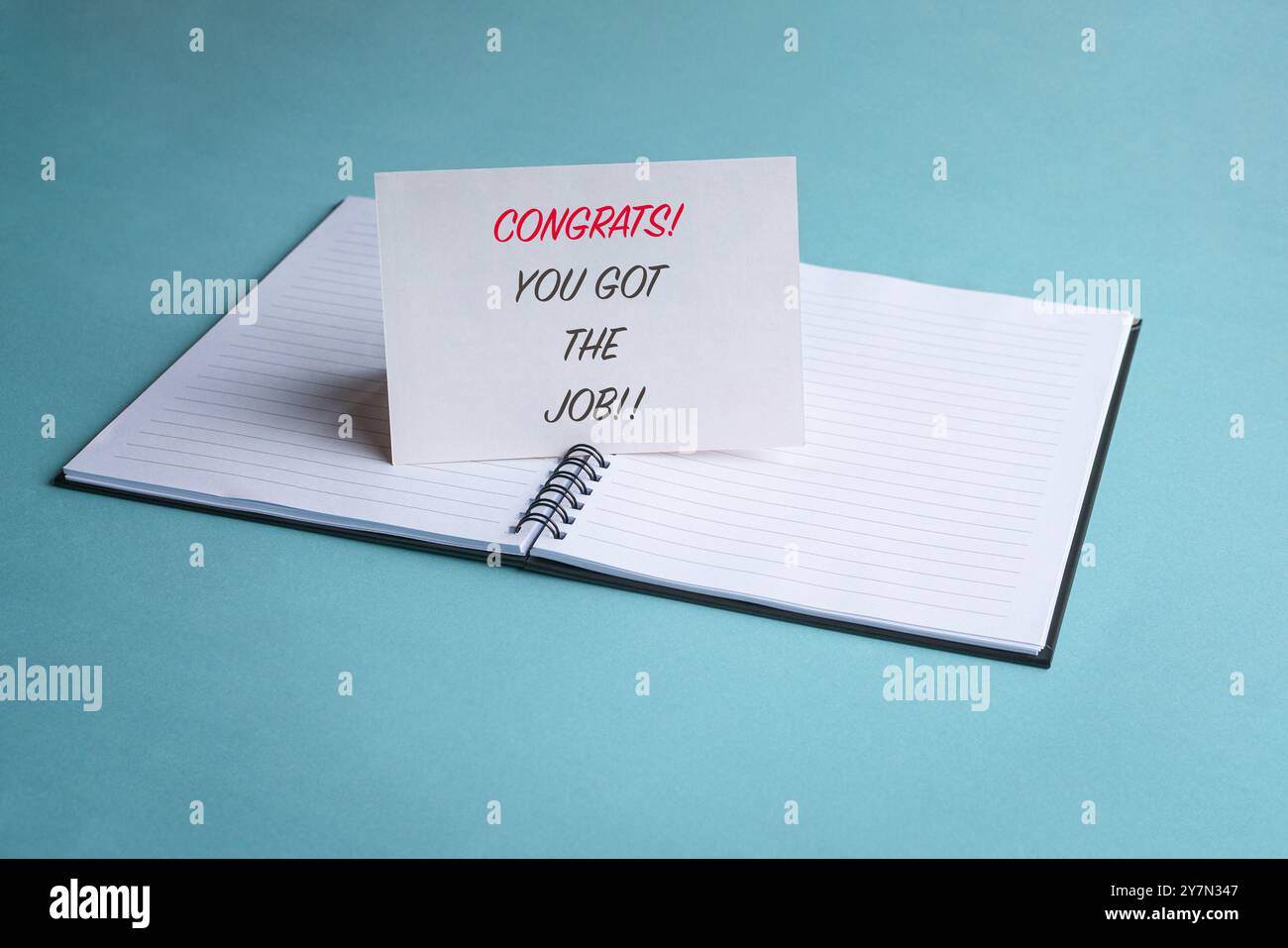 Congratulazioni, hai ottenuto il lavoro, un messaggio su una scheda bianca sopra un blocco note. Nuovo concetto di lavoro o occupazione. Foto Stock