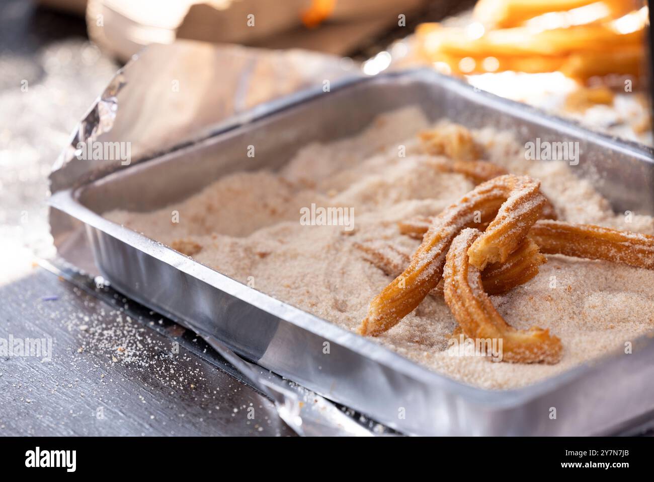 I churros appena fritti riposano in una padella di cannella e zucchero. Foto Stock