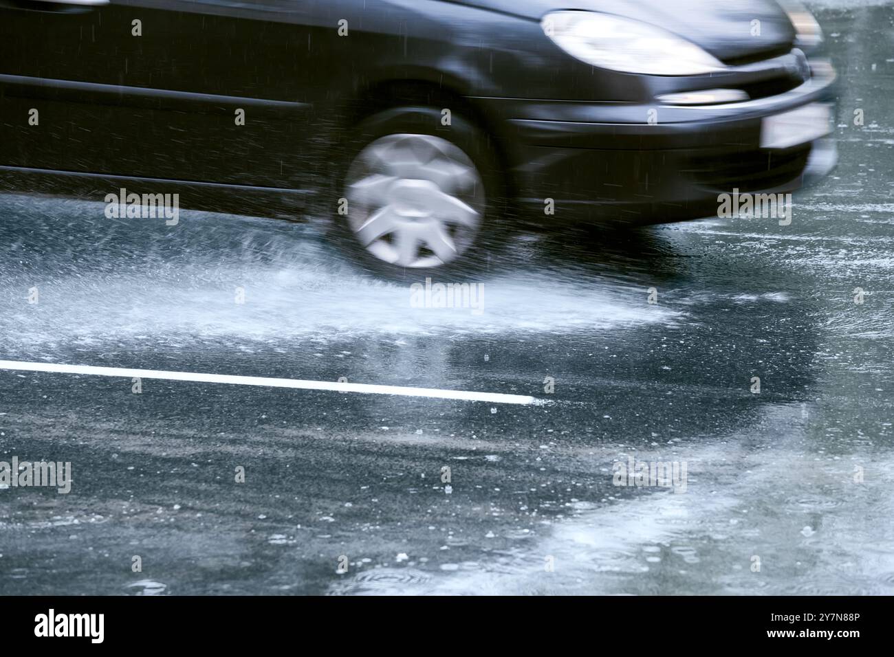 l'auto viaggia su una strada bagnata con spruzzi d'acqua. sfocatura del movimento. Foto Stock