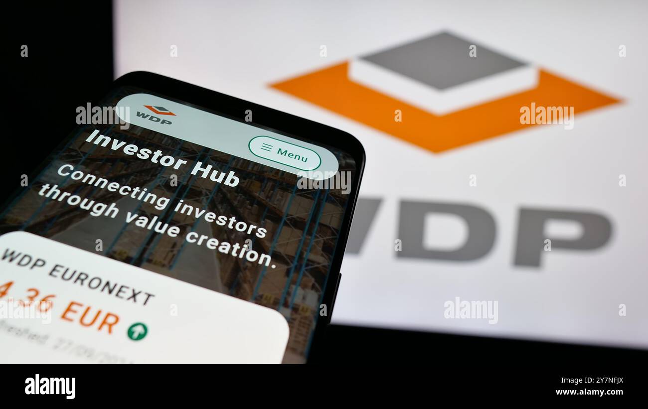 Smartphone con sito Web dei magazzini belgi De Pauw SA (WDP) sullo schermo davanti al logo aziendale. Mettere a fuoco in alto a sinistra sul display del telefono. Foto Stock
