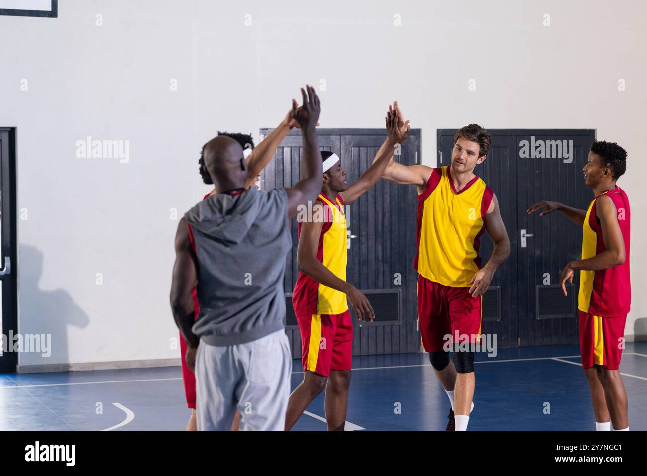 Compagni di squadra di alto livello, diversi giocatori di pallacanestro festeggiano durante gli allenamenti nella palestra scolastica Foto Stock