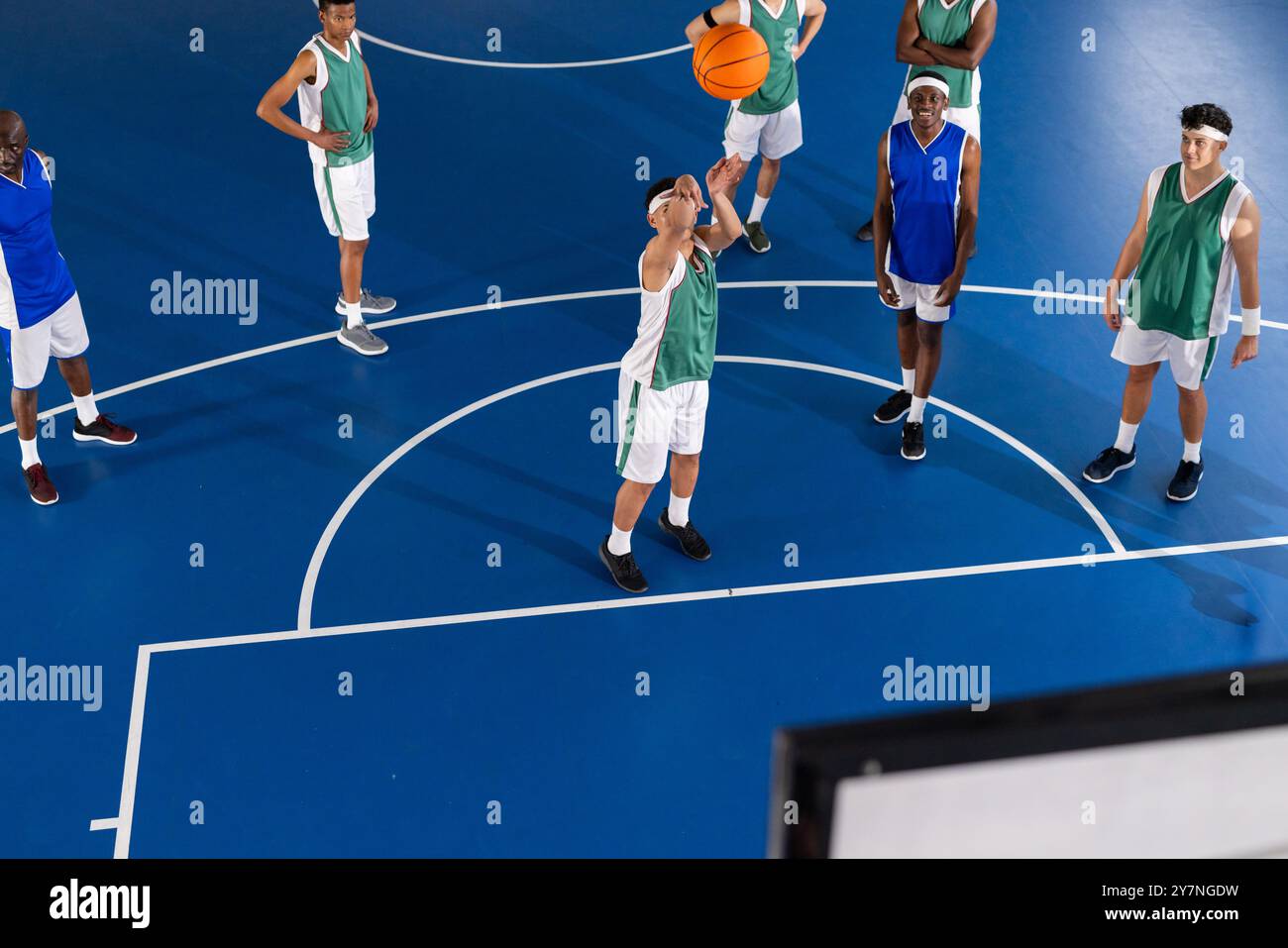 Giocando a basket, un gruppo di giocatori in uniforme che praticano sul campo coperto Foto Stock