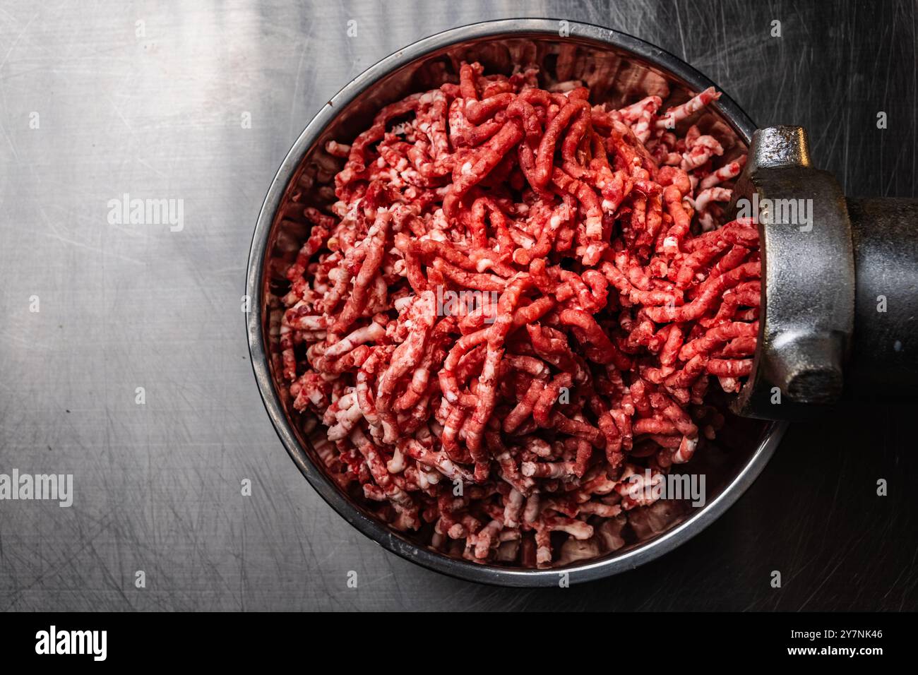 Macinatura della carne fresca in cucina con un moderno macinacaffè elettrico, dall'alto verso il basso Foto Stock