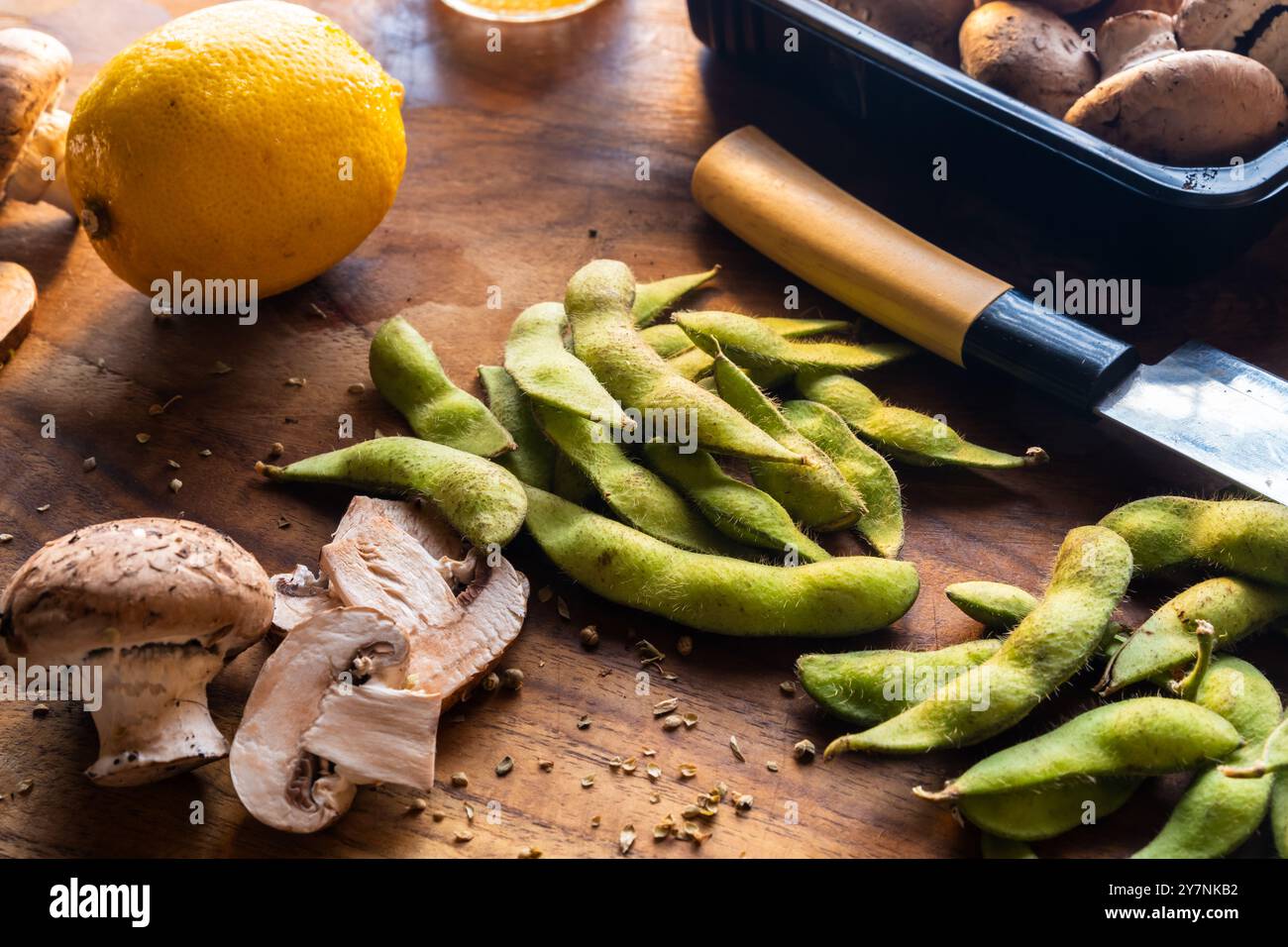 ha chiuso edamame fresco con altri ingredienti a base vegetale, su un tagliere di legno, preparando un concetto di cibo sano Foto Stock