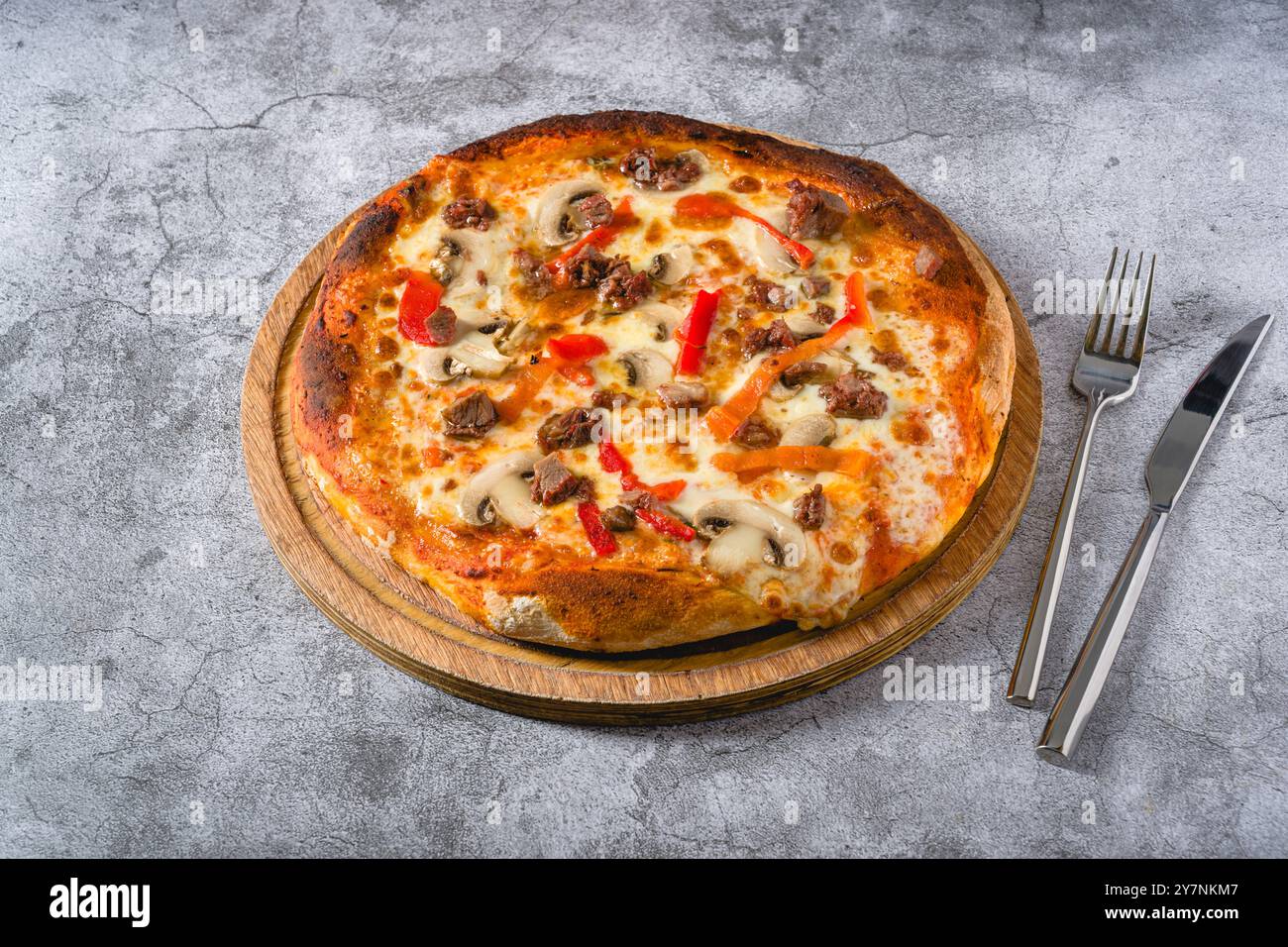 Pizza con paprika e roast beef su tagliere su tavolo di pietra Foto Stock
