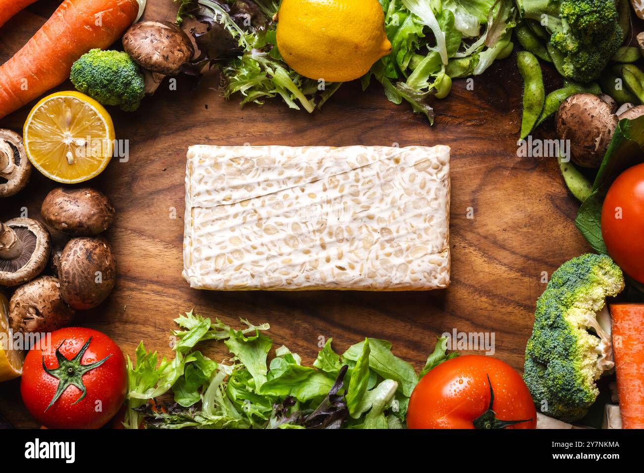 blocco di tempeh crudo con altri ingredienti vegetali su un asse di legno, concetto di cibo a base vegetale Foto Stock