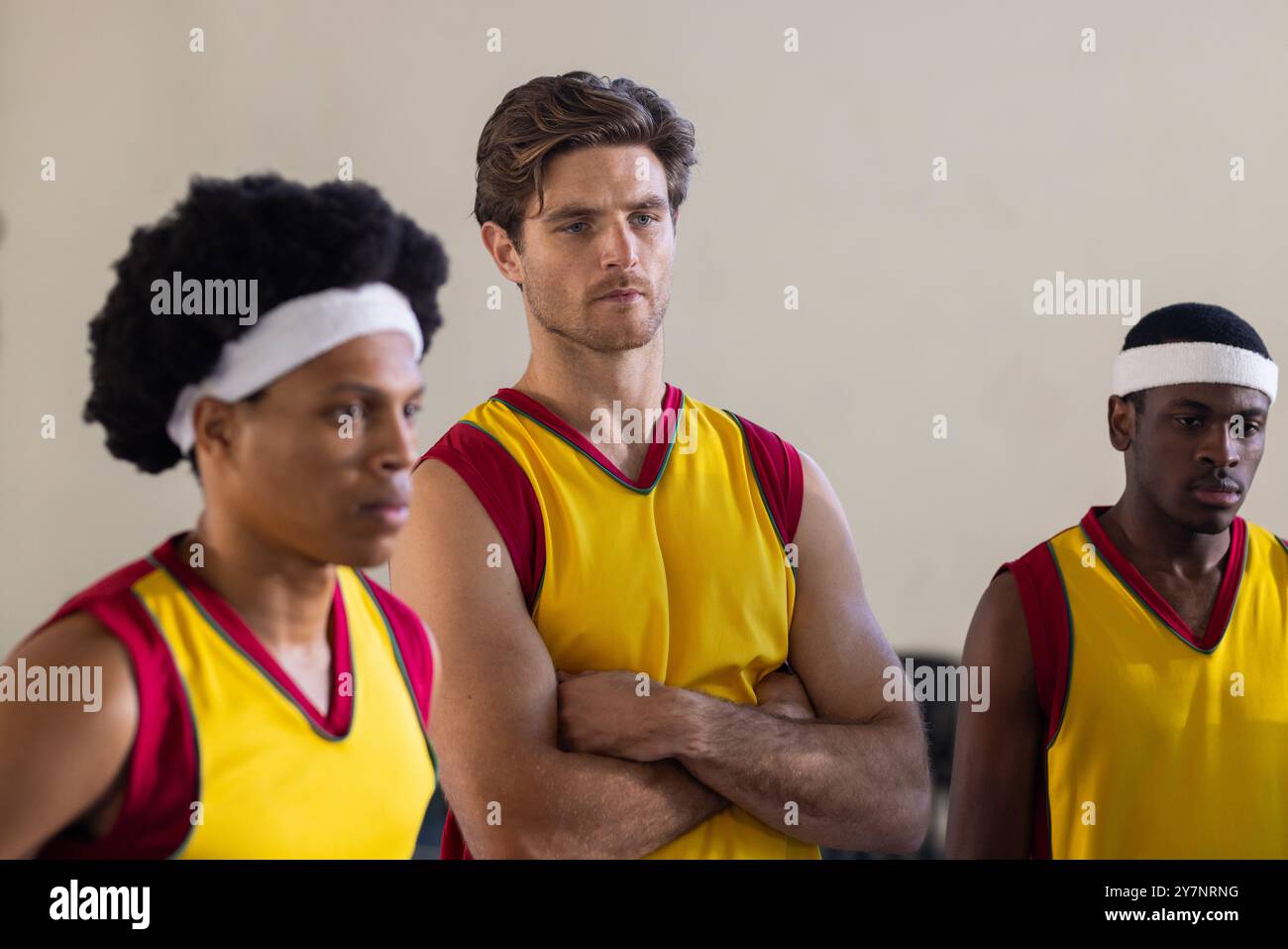 Diversi giocatori di pallacanestro con maglie gialle in piedi, concentrandosi sulla strategia di gioco Foto Stock