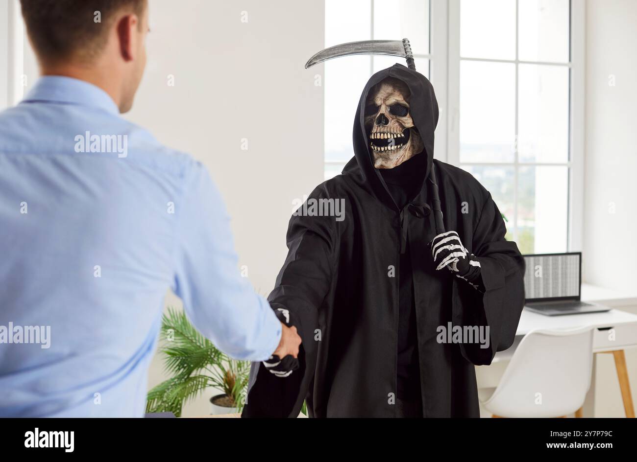Grim Reaper con una falce sulla spalla stringe la mano a un uomo d'affari nel suo ufficio Foto Stock