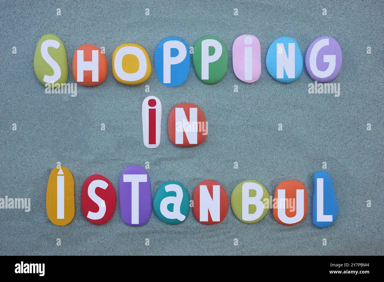 Shopping a Istanbul, design creativo con logo commerciale composto da lettere in pietra multicolore dipinte a mano su sabbia verde Foto Stock