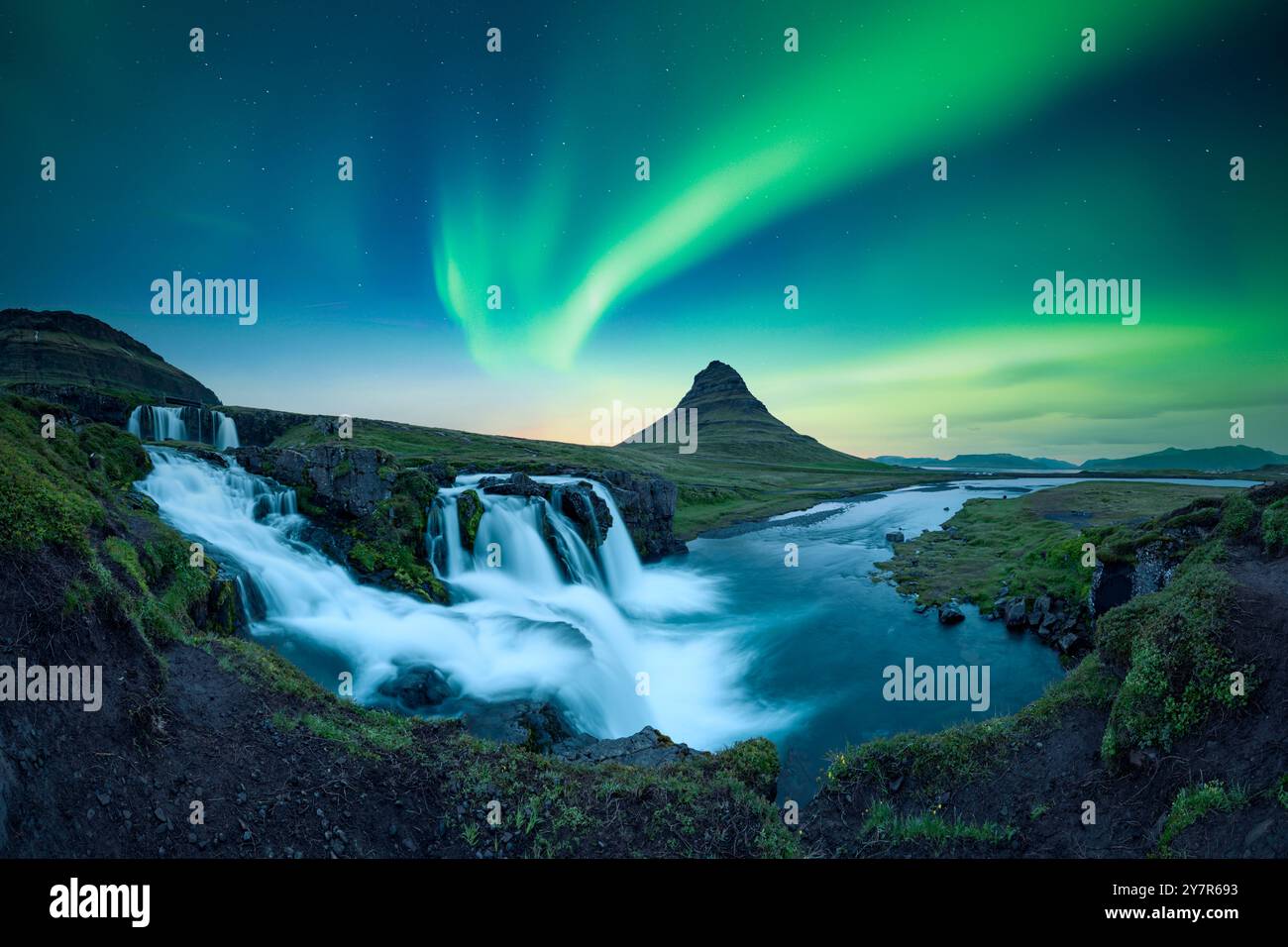 Vista panoramica della cascata di Kirkjufellsfoss sotto un cielo incredibile con l'aurora boreale. Incredibile paesaggio con il vulkano Kirkjufell e le luci polari in Islanda. Aurora boreale Foto Stock