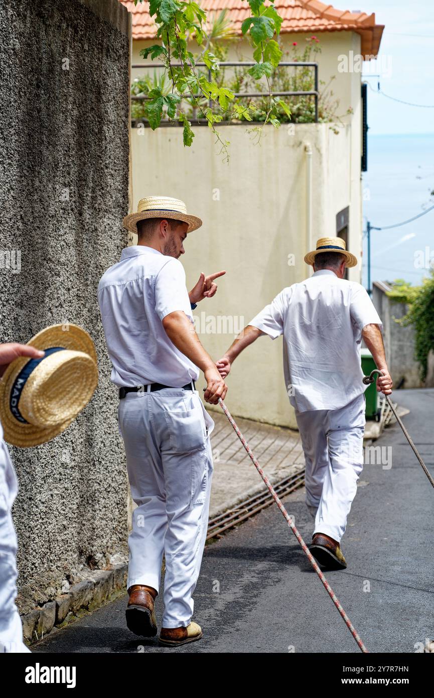 I Carreiros condividono un momento mentre si preparano per un altro giro in toboga in vimini lungo una strada tranquilla con vista sull'oceano Foto Stock
