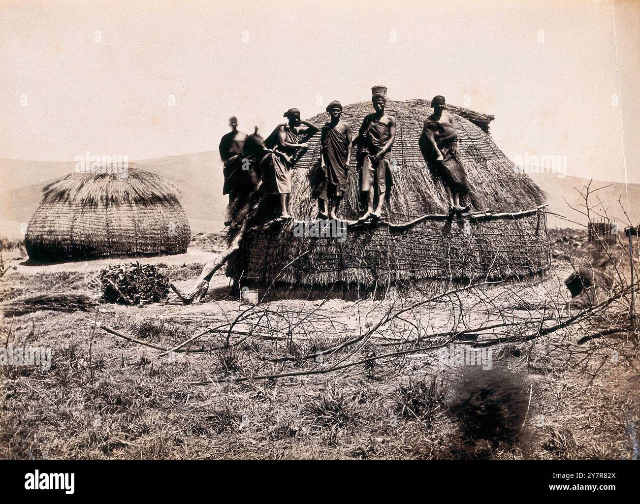 Fotografia d'epoca del Sudafrica: Un gruppo di africani in piedi su una capanna kraal. Tra il 1800 e il 1899 Foto Stock