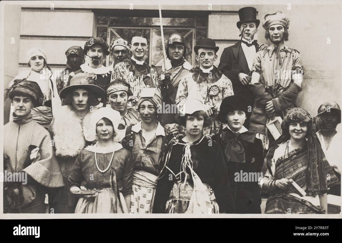 Le persone si sono riunite fuori da un edificio indossando vari costumi, alcuni in trascinamento. Cartolina fotografica, 1924 gli attori, che interpretano una varietà di personaggi, sono in primo piano per questo ritratto di gruppo. Probabilmente un gala in abito elegante piuttosto che una produzione teatrale, in una location non identificata (britannica). Palle in costume e gala godettero di una particolare voga negli anni '1920 Uomini e donne sono entrambi vestiti in croce Foto Stock