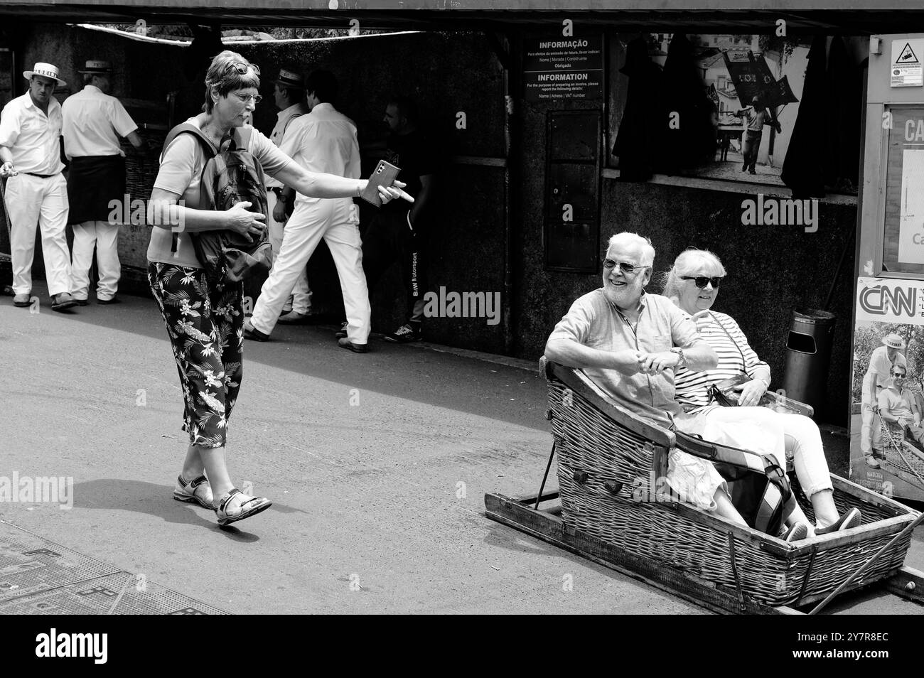 Monocromatico, che cattura i sorrisi prima del giro, i turisti maturi partono su una tradizionale slitta in vimini Foto Stock