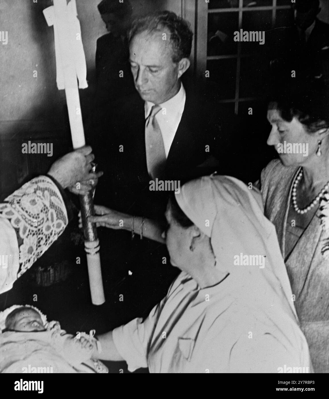 LA PRINCIPESSA DI LUSSEMBURGO BATTEZZATA 22.2,54. La figlia di cinque giorni del principe Jean e della principessa Giuseppina di Lussemburgo fu battezzata sabato. Alla cerimonia battesimale nel Palazzo Betzdorf del Principe Jean, fu chiamata Marie Astrid Charlotte Leopoldine Wilhelmine Ingeborg Antonia Elsa Elizabeth Anna. Il suo padrino era l'ex re Leopoldo del Belgio, che è suo nonno. LA FOTO MOSTRA I.N.P. - i genitori della piccola principessa tengono una candela cerimoniale su di lei. 494/MB/74709 International News Photos. Foto Stock