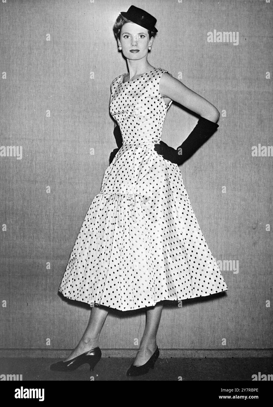 LA STORIA DI PRIMAVERA CON SIMBOLI FORTUNATI. Hubert de Givenchy è pronto per una corsa di fortuna con una selezione fresca e ben personalizzata di stili primaverili. Utilizza simboli di buona fortuna: Quadrifoglio, pesce, orecchie di frumento, tartaruga e giglio della valle. La linea di quest'anno è accarezzata, molto spesso con aggiunte divertenti - colletti da marinaio, sciarpe organdie, un garofano fissato sul retro del collare, ecc.. La scena serale è generosa in linea con l'interesse alla schiena. FOTO DI I.N.P. - taffeta di seta bianca con punti neri. Il corpetto, senza maniche, si adatta alla forma. La gonna è incastonata nella principessa Foto Stock