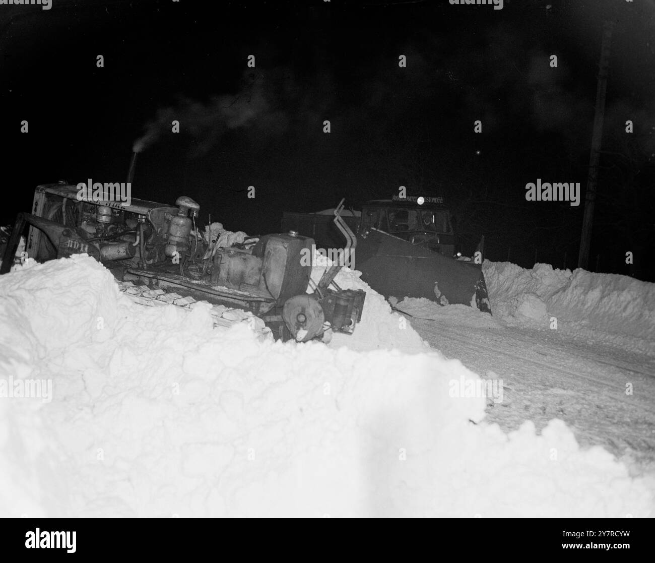 LO SPAZZANEVE LAVORA TUTTA LA NOTTE PER LIBERARE GHIACCIO E NEVE DAI VILLAGGI ABBANDONATI DEL KENT. 4,2.54. Spettacoli fotografici I.N.P. Sotto il bagliore delle luci ad arco, gli aratri della neve vengono fotografati al lavoro ripulendo la neve e il ghiaccio da Charing Road, Kent. Foto di S. S. S. Heydinger. Foto di notizie internazionali. (Speciale). 74353. Foto Stock