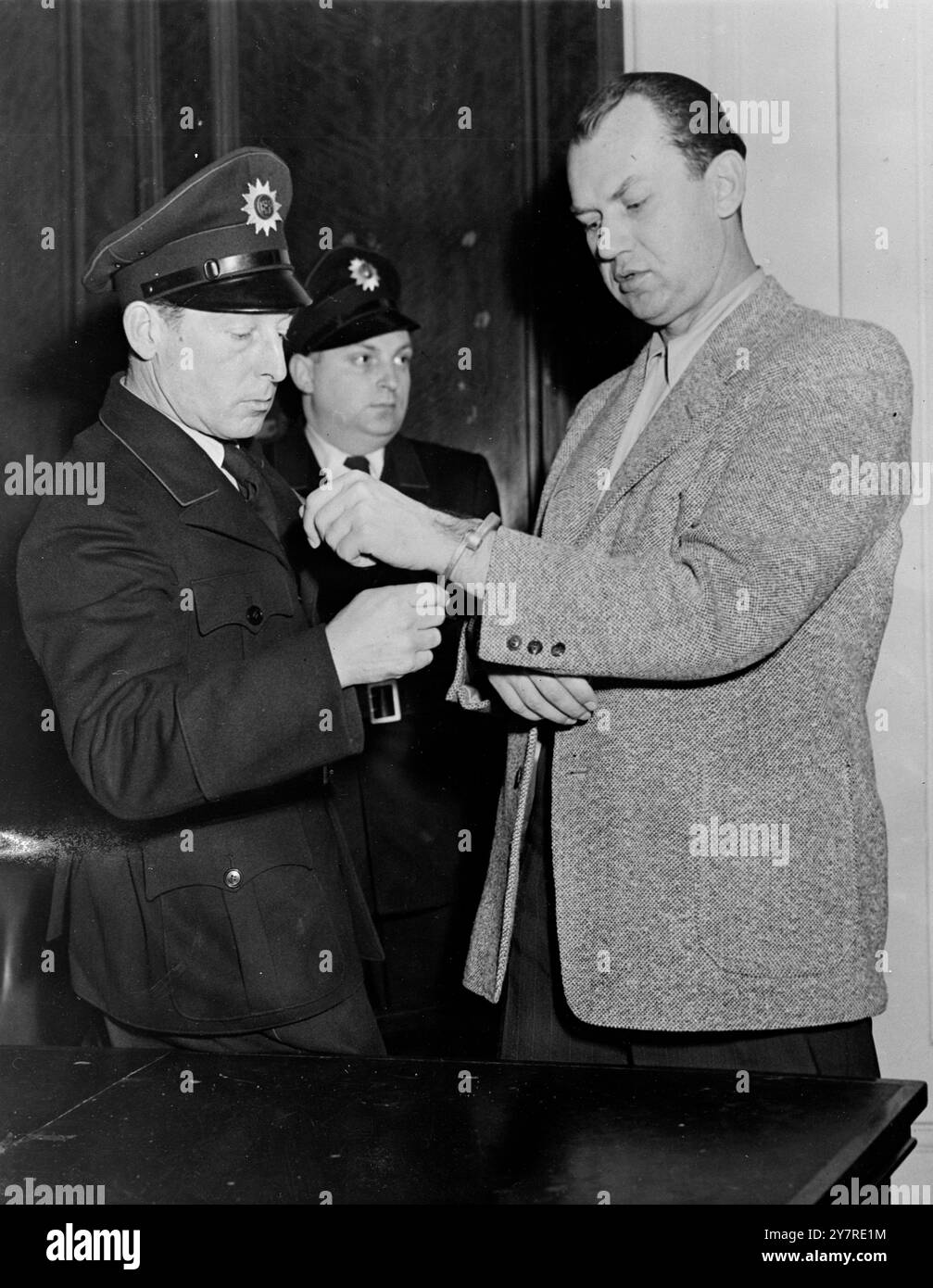 KHORUNZHI CONDANNATO A 14 ANNI PER SPIONAGGIO. Il 23 gennaio 1954, un tribunale distrettuale dell'alta Commissione degli Stati Uniti a Francoforte ha condannato ieri Georgi Vladimirovich Khorunzhi, alias George Mueller, a 14 anni di reclusione dopo averlo dichiarato colpevole di attività di spionaggio a nome dell'Unione Sovietica e diretto contro le forze statunitensi in Germania. Sua moglie, Elisabeth Mueller, ricevette due anni. La foto di I.N.P. mostra che Khorunzhi viene ammanettato da un poliziotto tedesco dopo la sua condanna. Foto di notizie internazionali. Foto Stock