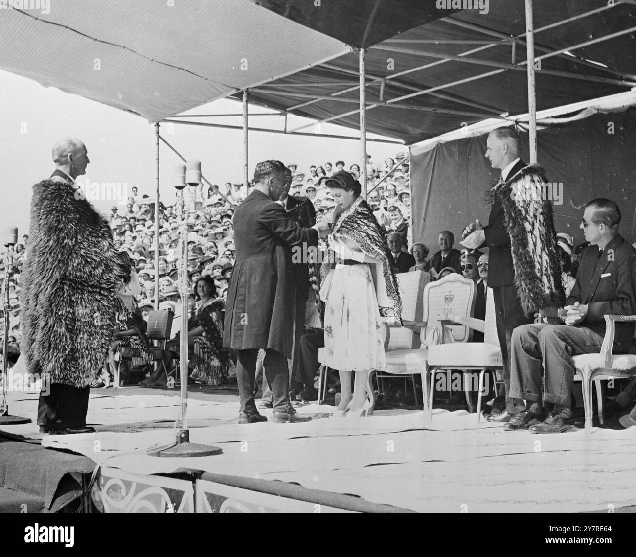 TOUR REALE. 7,1.54. Il ricevimento Maori ad Arawa Park, Rotorua, quando la Regina e il Duca di Edimburgo furono cerimonialmente drappeggiati con il Cloak Korowai, dal Vescovo di Aotearoa (RT Rev. Wiremu Panapa). Il mantello è il simbolo del rango fondamentale. Piscina/piano/EW 73726. Foto di notizie internazionali. Foto Stock