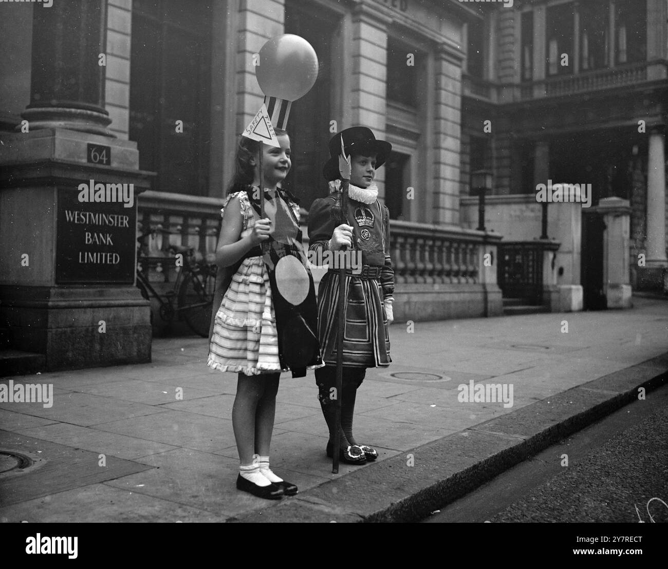 CARA PORTA IL SUO FARO. 6,1.1954, trecento bambini hanno partecipato alla festa annuale della Lega della pietà, il ramo minore della National Society for the Prevention of Cruelty to Children, tenutasi all'Hyde Park Hotel di Londra, questo pomeriggio. I profitti del partito vanno ai fondi della società. La foto di I.N.P. mostra che cara Mounsey di otto anni ha trovato il suo vestito elegante di un Belisha Beacon utile per attraversare le strade sulla strada per la festa con Yeoman della Guardia, David Roberts di nove anni. I Belisha Beacons sono usati per indicare attraversamenti pedonali sulle strade britanniche. Immagine di Reg Palmer, PJ/7 Foto Stock
