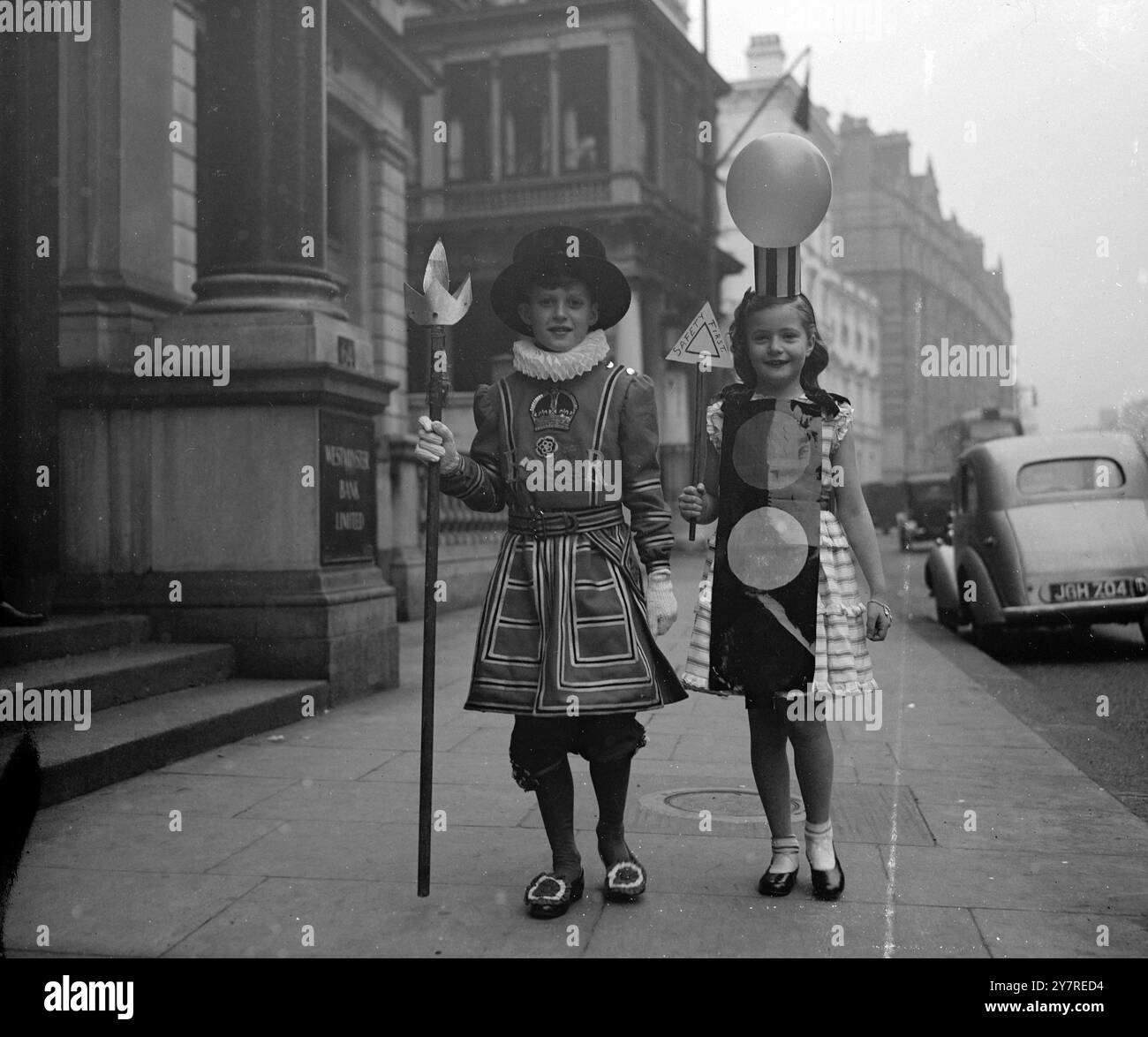 CARA PORTA IL SUO FARO. 6,1.1954, trecento bambini hanno partecipato alla festa annuale della Lega della pietà, il ramo minore della National Society for the Prevention of Cruelty to Children, tenutasi all'Hyde Park Hotel di Londra, questo pomeriggio. I profitti del partito vanno ai fondi della società. La foto di I.N.P. mostra che cara Mounsey di otto anni ha trovato il suo vestito elegante di un Belisha Beacon utile per attraversare le strade sulla strada per la festa con Yeoman della Guardia, David Roberts di nove anni. I Belisha Beacons sono usati per indicare attraversamenti pedonali sulle strade britanniche. Immagine di Reg Palmer, PJ/7 Foto Stock