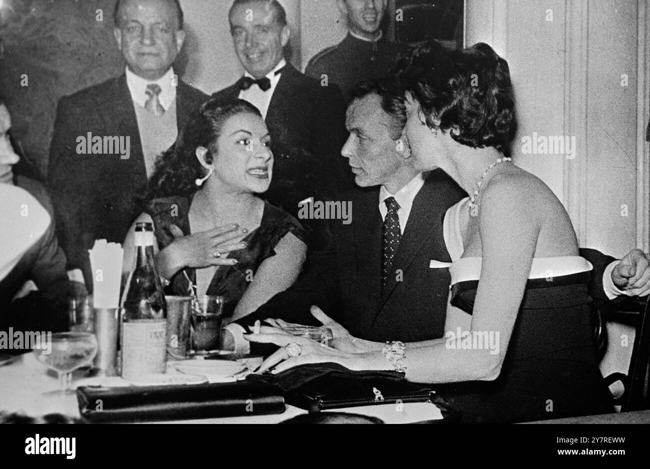 Riconciliazione esclusiva per Frankie e Ava??? 28.12.53. Dopotutto Frank Sinatra e Ava Gardner si riconcilieranno? Frankie ha noleggiato un aereo per volare dall'America a Madrid, dove Ava alloggiava, e l'ha portata in giro per i locali notturni di Madrid e in questa foto è visto seduto con il braccio intorno ad Ava Gardner in un nightclub di Madrid. La famosa ballerina spagnola Lola Flores parla con Frank Sinatra e Ava Gardner al night club Pasapoga di Madrid. Nota il braccio di Frankie intorno ad Ava. 7/Special/W/73498 International News Photos. Foto Stock