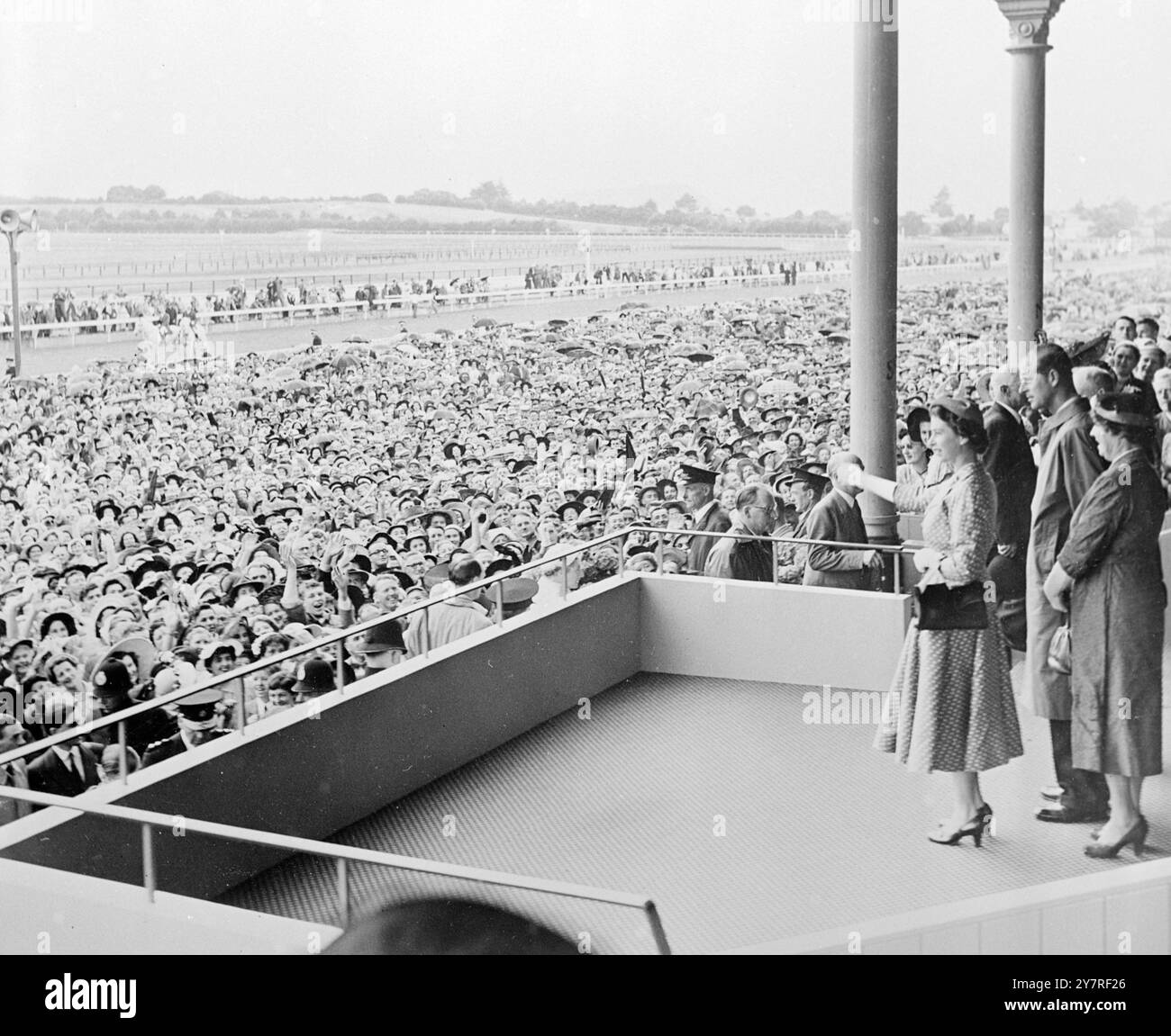 La regina alle corse in nuova Zelanda. Per il momento, le corse sono dimenticate, mentre tutti gli occhi sul circuito di Ellerslie, Auckland, nuova Zelanda, si rivolgono al box appena entrato H.M. The Queen. Una folla di 70.000 persone ha partecipato alla riunione del Boxing Day (dicembre 26) nonostante i cieli ricoperti e le frequenti docce, e hanno salutato la Regina con applausi e canti. PJ/73558 pubblicato da Press Photo Combine. Foto Stock