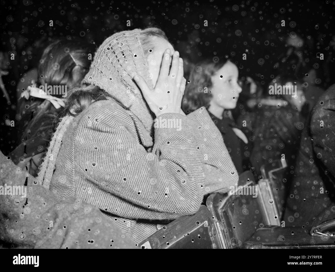 Non posso sopportare, ma devo sbirciare. Valerie Bonner, di Willesden, di otto anni, non sopporta di guardare e non sopporta di non farlo, quindi si mette a compromessi sbirciando con le dita in uno dei concerti del Bertram Mills Circus di Olympia, Londra. Immagine di Reg Palmer. PJ 73354. Foto di notizie internazionali. Foto Stock